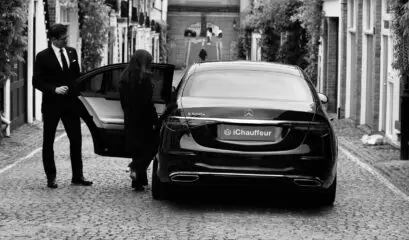 Chauffeur opening Mercedes S-Class door for passenger