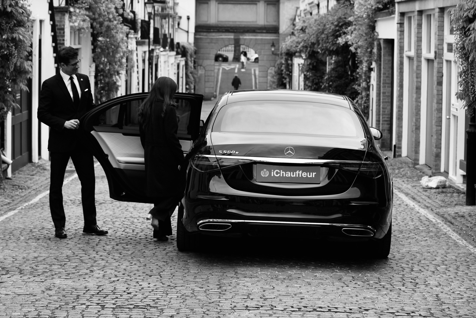 Chauffeur opening Mercedes S-Class door for passenger